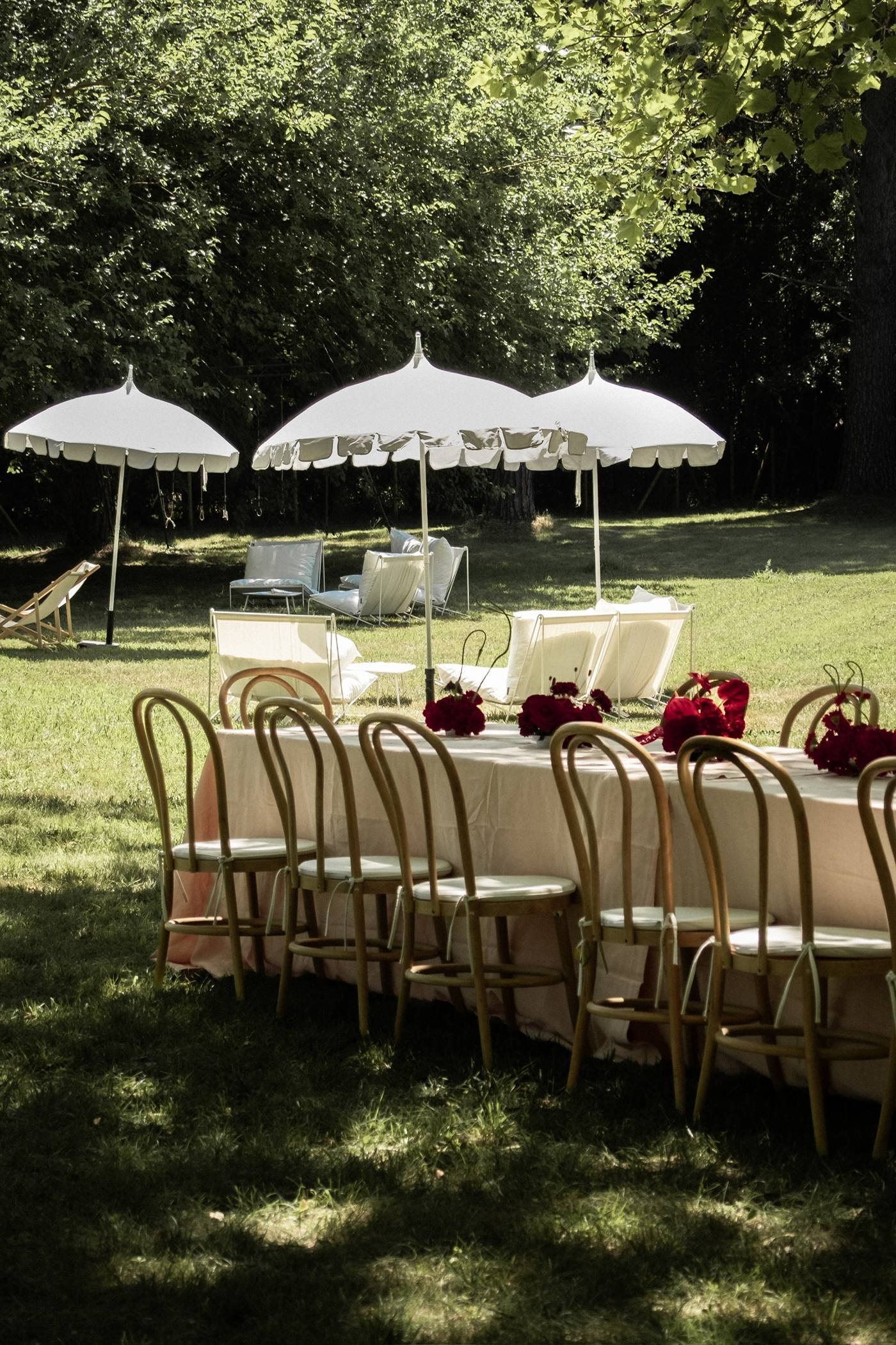 Parasols blancs et longue table dressée dans un parc