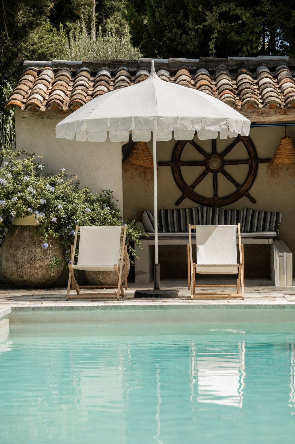 Piscine, parasol blanc et transats au bord d'une bastide